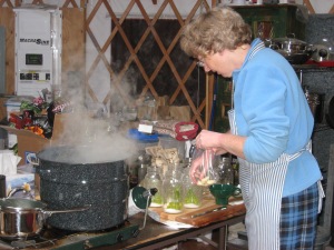 Jenny adding dill from are garden, pickling salt, and a garlic clove to the jars.